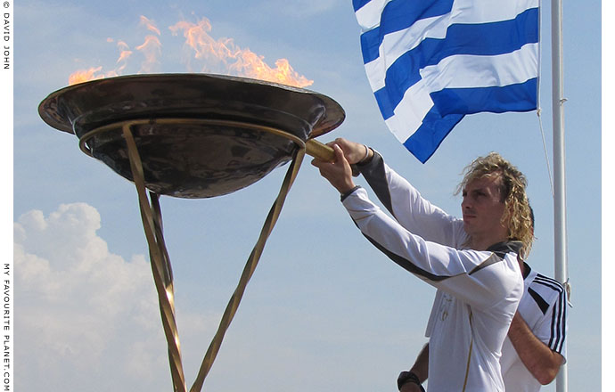 Greek torchbearer Ioannis Melissanidis lights his torch to take the Olympic flame to Kavala, Macedonia, Greece, at The Cheshire Cat Blog